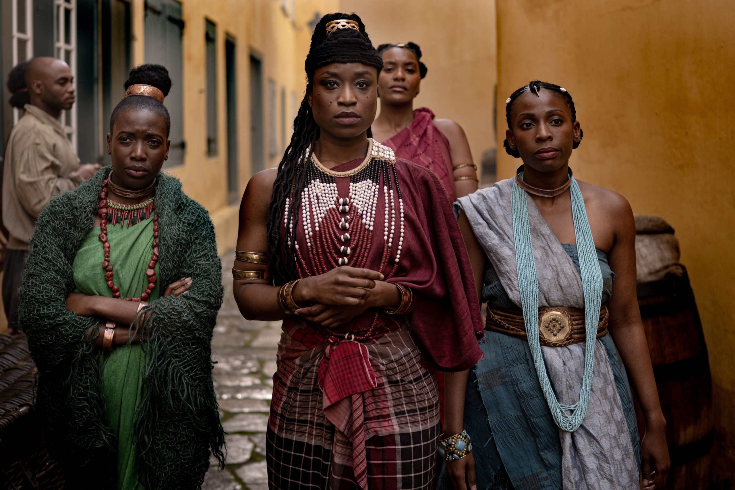 African Queens: Njinga. (Center) Njinga (ADESUWA ONI), Ndambi (ESHE ASANTE), Kambu (CHIPO KUREYA) & Funji (MARILYN NNADABE) walk through the streets and encounter a row of slaves. in African Queens: Njinga. Cr. Joe Alblas/Netflix © 2023
