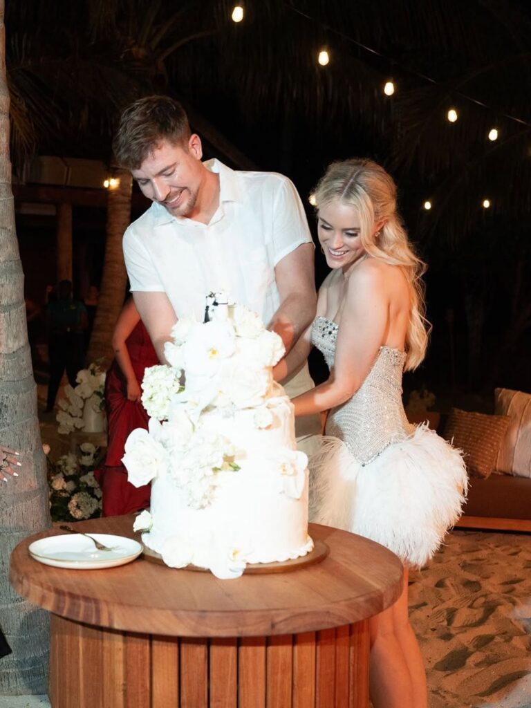 MrBeast (Jimmy Donaldson) and his wife, Thea Booysen, smile as they cut their wedding cake during their private seaside wedding reception.